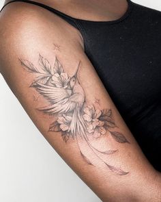 a woman's arm with a bird and flowers tattoo on the left side of her arm