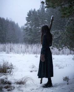 a woman standing in the snow pointing at something