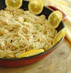 a pan filled with pasta and lemons on top of a wooden table