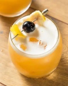 two glasses filled with drinks on top of a wooden table