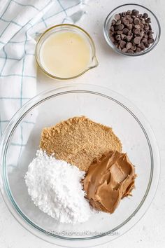 ingredients to make chocolate peanut butter cookies on a white tablecloth and glass bowl with milk