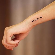 a person's arm with an arrow tattoo on the left side of their wrist