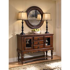 a bowl of fruit sits on top of a wooden cabinet in front of a mirror