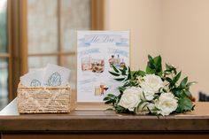 a bouquet of white flowers sitting on top of a wooden table next to a sign