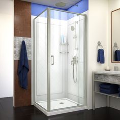 a bathroom with a walk in shower next to a white sink and blue towels on the counter