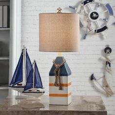 there is a lamp on the table next to two boats and a book shelf with books