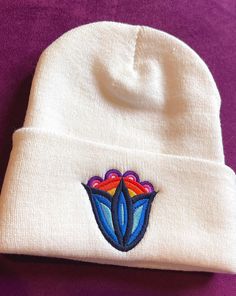 The Beanie will keep you warm & cozy. You will top off their look with this classic beanie. Super dense to offer the best embroidery canvas. Almost all apparel is printed via DTG printing- please see page FAQs for more info! (All over prints may be printed via dye sublimation.) This is important to note, as it is different from screen printing and has a different look. :)  The mockups feature a digital graphic, and will look more "vintage" on the actual garment.  Bizaanide'ewin is a Native small Ojibwe Floral, Woodland Flowers, Cultural Appropriation, Blue Tulips, Floral Hat, Indigenous Art, Winter Beanie, Native Art, Winter Weather