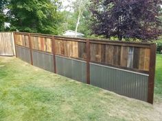 a fence made out of wooden boards and metal bars on the side of a yard