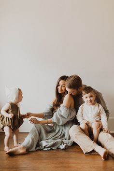 a family sitting on the floor in front of a white wall