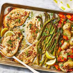 chicken and asparagus on a sheet pan with lemon wedges