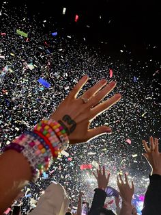 confetti being thrown in the air at a concert, with hands raised up