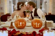 a bride and groom kissing in front of their mr and mrs pumpkins on the table