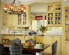 a dining room table and chairs in a kitchen with yellow cabinets, blue checkered upholstered arm chairs