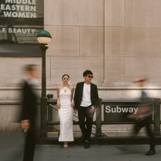 a man and woman standing next to each other in front of a sign that says subway