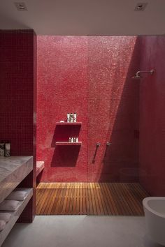 a red tiled bathroom with wooden flooring and shelves on the wall, along with a white bathtub