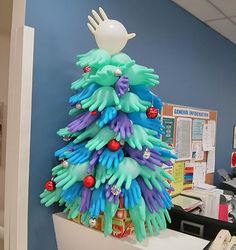 a christmas tree made out of plastic gloves on top of a desk in an office