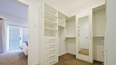 an empty white closet with lots of drawers and shelves on the wall next to it