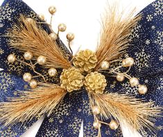 a blue and gold bow with pinecones on the top is adorned with golden balls