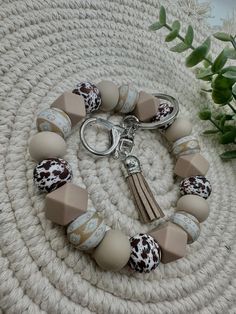 a white and brown bracelet with tassels on it sitting on a table next to a potted plant