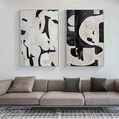 two abstract paintings hang on the wall above a couch