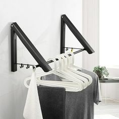 there is a black and white rack with clothes hanging on it next to a table