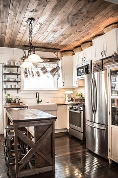 a kitchen with white cabinets and wood floors, an island in front of the stove