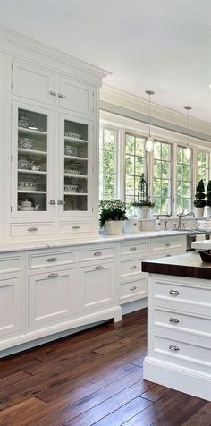 a large white kitchen with wooden floors and cabinets in the center, along with an island