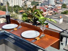 two white plates and silverware on a wooden table with cityscape in the background