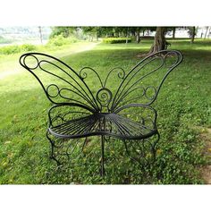 a metal butterfly bench sitting on top of a lush green grass covered park field next to a tree