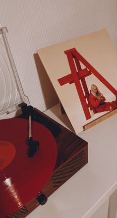 an old record player sitting on top of a table next to a red vinyl album