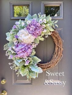 a wreath with purple flowers and greenery on the front door to a house that says sweet & sassy