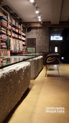 a long counter in a store filled with lots of books on shelves next to a chair