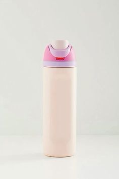 a white and pink cup sitting on top of a table next to a bottle filled with liquid