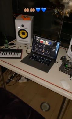 an open laptop computer sitting on top of a desk next to speakers and music equipment