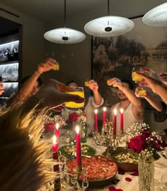 a group of people are toasting at a table with food and candles on it