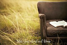 an open book sitting on top of a leather chair in the middle of a field