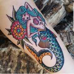 a woman is sitting on top of a fish with flowers in her hair and holding onto the tail