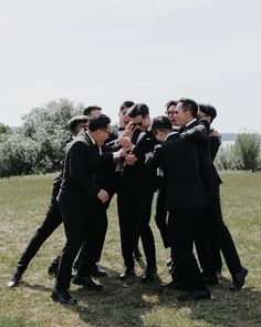 a group of men in suits and ties standing next to each other on top of a grass covered field