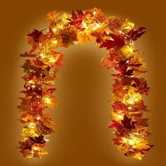 an arch made out of leaves with lights in the shape of autumn leaves on it