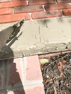 a bird standing on the side of a brick building next to a pile of debris