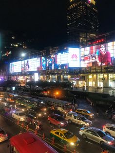 a busy city street filled with lots of traffic and tall buildings lit up at night