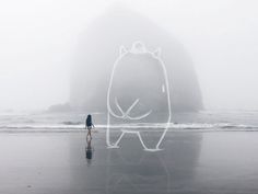 a person standing on the beach with a drawing of a cat in front of them