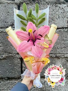 a person holding a bouquet of flowers in front of a brick wall with a butterfly on it