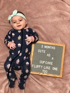 a baby is laying down next to a sign that says 3 months cute as a cupcake