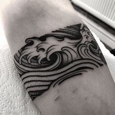 a black and white tattoo on the arm of a man with waves coming out of it