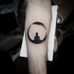 a person with a tattoo on their arm sitting in front of a black and white circle