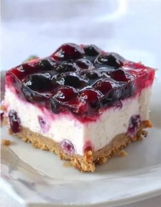 a piece of cheesecake on a plate with blueberries and cherries in it