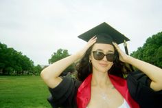 a woman wearing sunglasses and a graduation cap is holding her hands up to her head