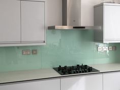 a kitchen with white cabinets and green glass backsplashes on the counter top