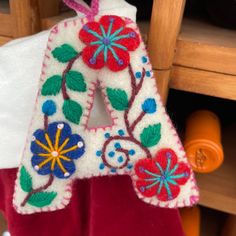 an embroidered letter hanging from a wooden chair